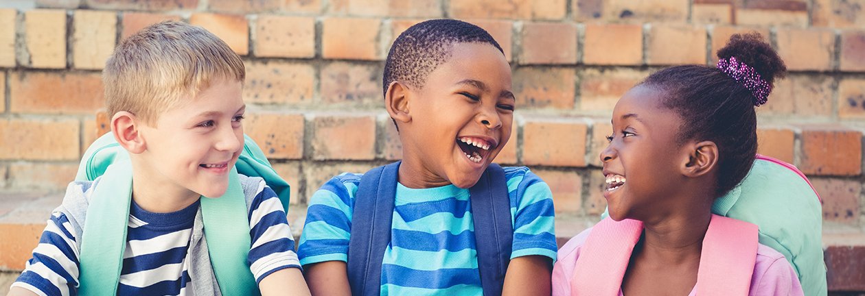 three kids with backpacks laughing