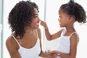 mother and daughter with pretty skin applying lotion to face