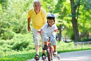 older male teaching young boy to ride bike