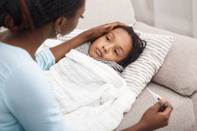 Sick girl laying on couch, with mother touching her head