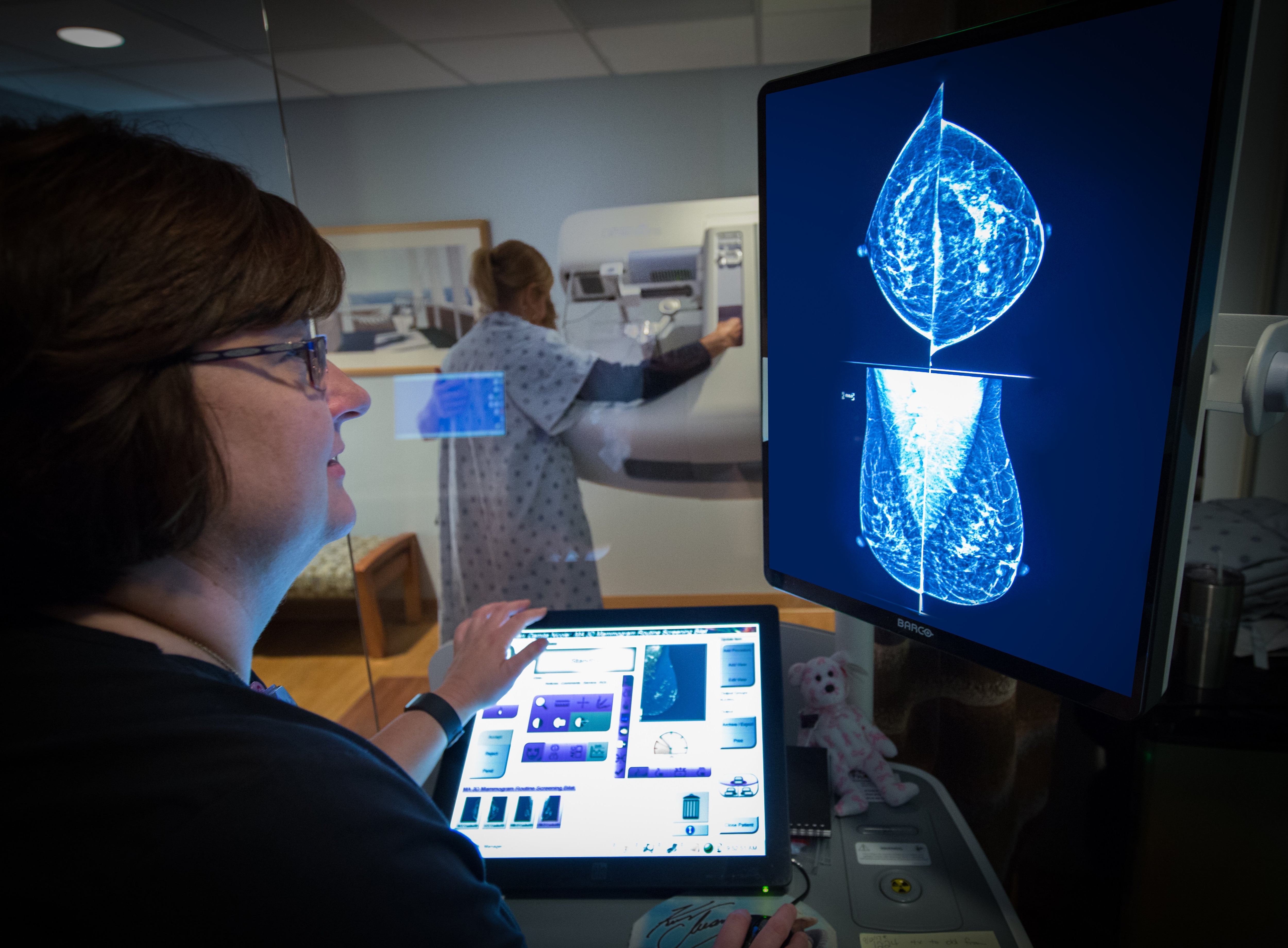 mammography technician performs 3d mammogram on woman