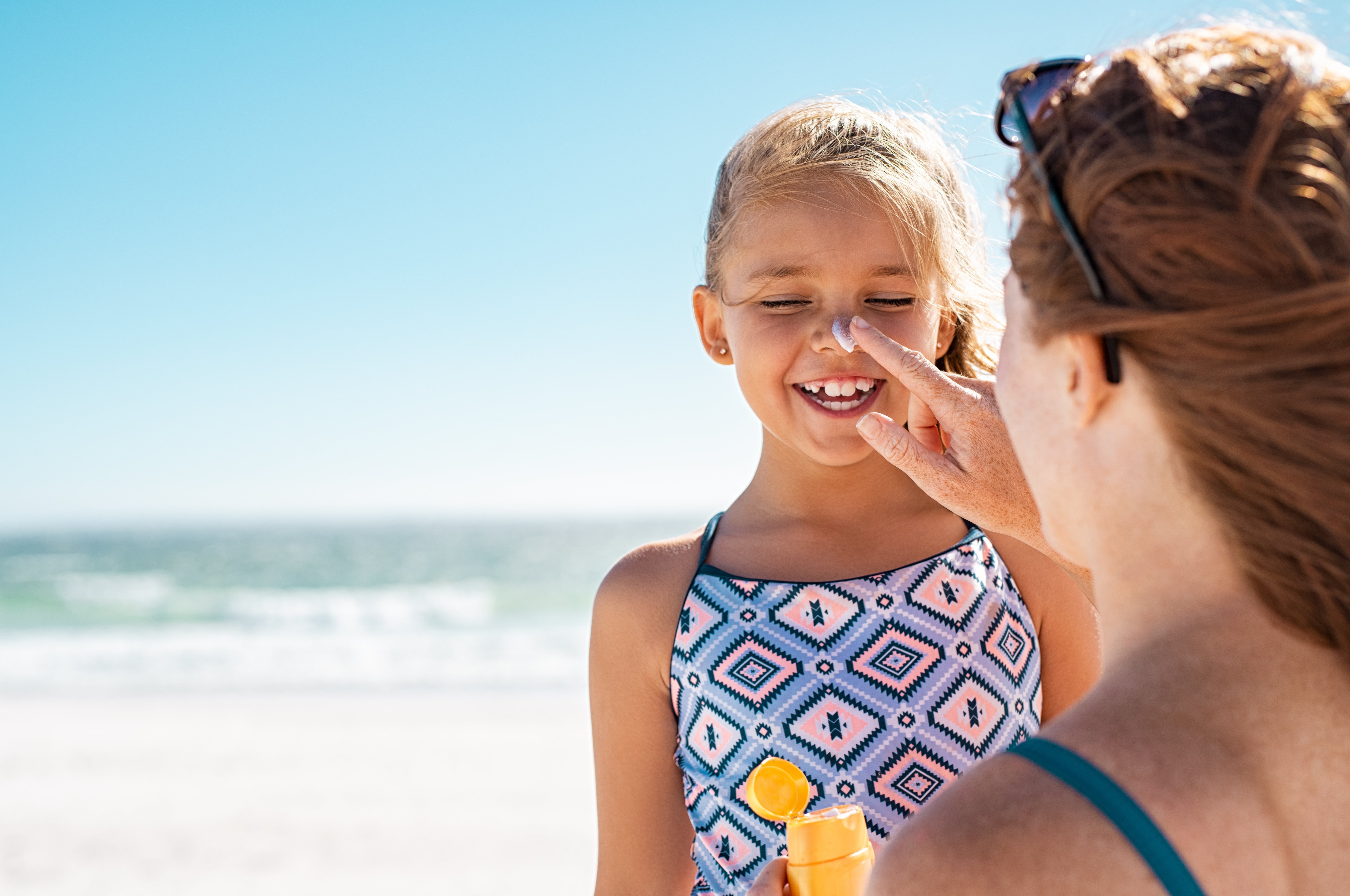 Mom applying sunscreen to daughter's face